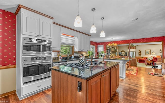 kitchen featuring wallpapered walls, cooktop, light wood-style floors, a peninsula, and a kitchen island