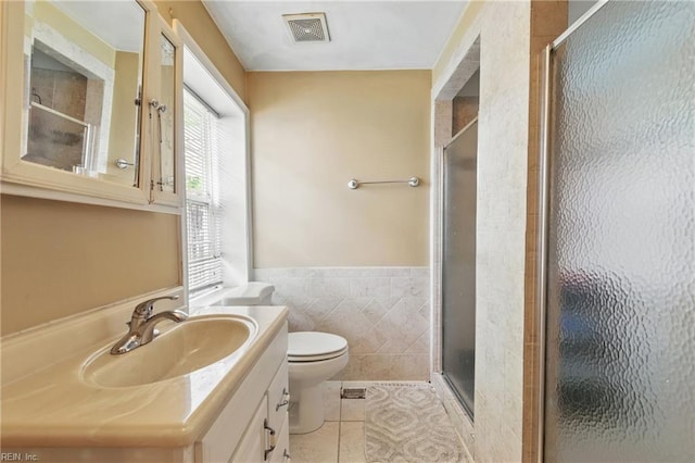 full bathroom featuring a stall shower, vanity, toilet, tile patterned floors, and wainscoting