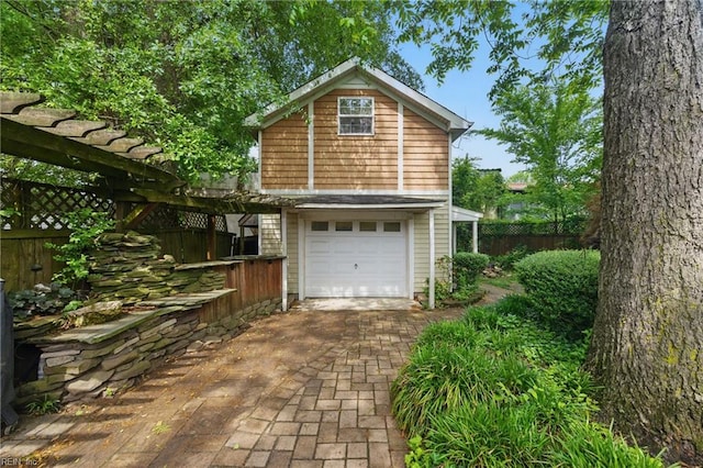garage featuring fence and decorative driveway