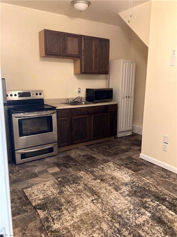 kitchen featuring stainless steel appliances, dark brown cabinetry, baseboards, and a sink