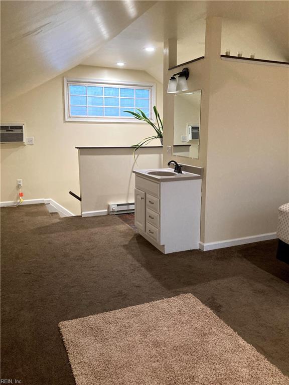 bathroom with baseboard heating, baseboards, vaulted ceiling, vanity, and a wall mounted AC