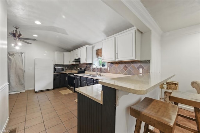 kitchen featuring stainless steel appliances, a sink, backsplash, vaulted ceiling, and a peninsula