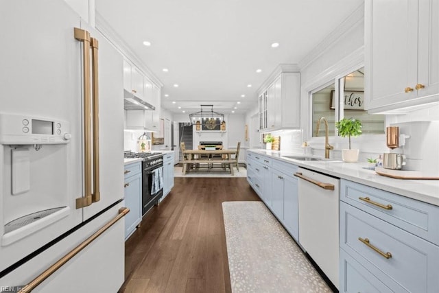 kitchen featuring white appliances, a sink, recessed lighting, white cabinetry, and dark wood-style flooring