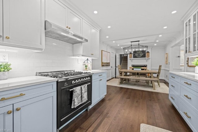 kitchen featuring under cabinet range hood, range with two ovens, light countertops, white cabinetry, and dark wood finished floors