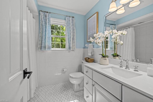 bathroom with tile walls, toilet, vanity, a shower with curtain, and wainscoting