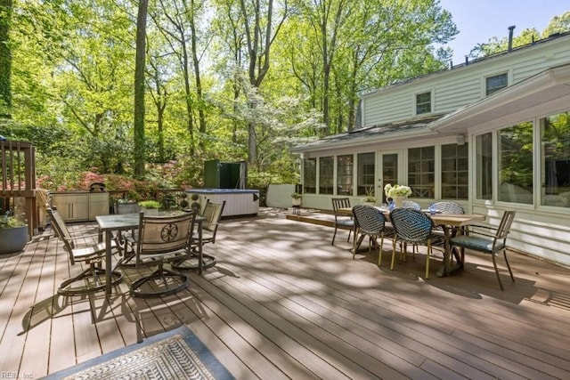 deck featuring outdoor dining area, a hot tub, and a sunroom
