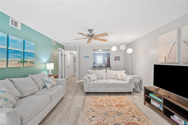 living room featuring light wood-type flooring, a ceiling fan, and baseboards