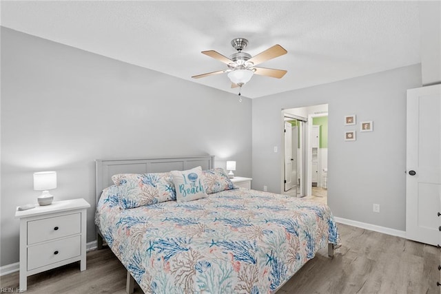 bedroom with wood finished floors, baseboards, ceiling fan, and ensuite bath