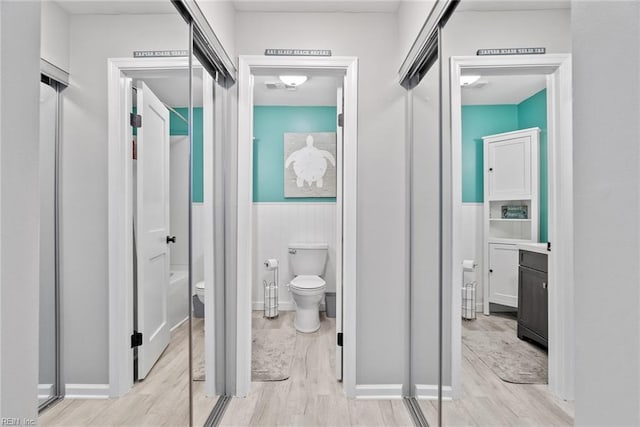 bathroom with toilet, a wainscoted wall, wood finished floors, and vanity