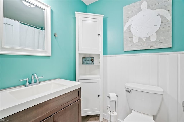 bathroom with wainscoting, toilet, and vanity