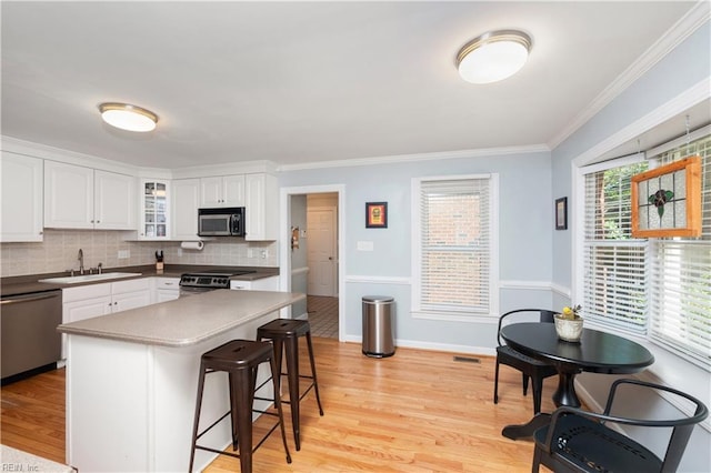 338 W Olney Rd, Norfolk, VA 23507 - kitchen featuring stainless steel appliances, a sink, a kitchen breakfast bar, light wood finished floors, and white cabinets