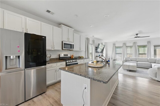 kitchen featuring appliances with stainless steel finishes, white cabinetry, light wood-style flooring, an island with sink, and recessed lighting