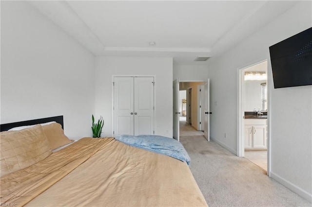 unfurnished bedroom with light colored carpet, a closet, a tray ceiling, and baseboards