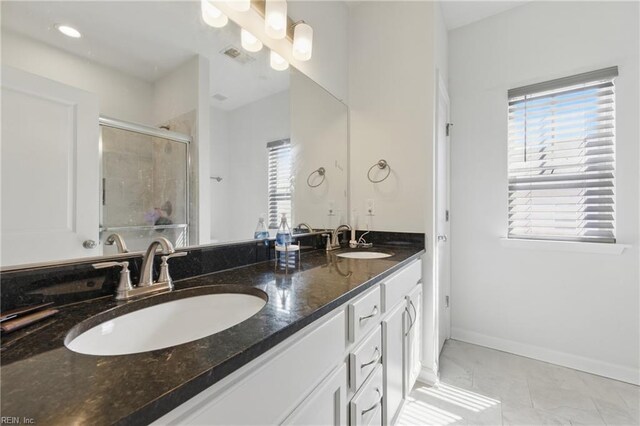 full bath featuring a stall shower, double vanity, and baseboards
