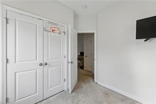 unfurnished bedroom featuring light colored carpet, baseboards, and a closet