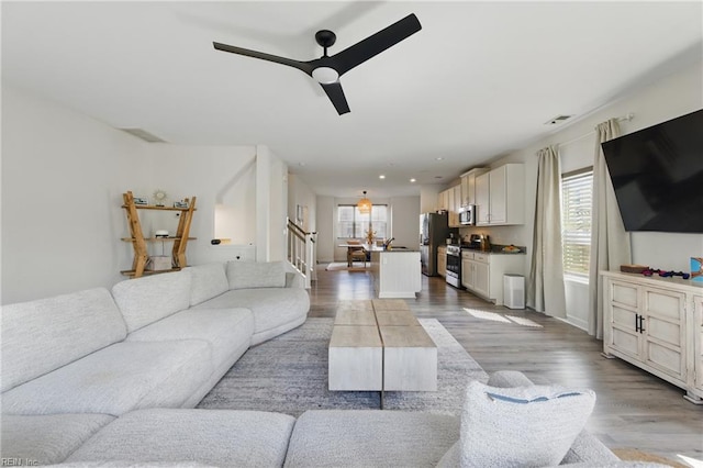 living area featuring wood finished floors, stairs, a ceiling fan, and recessed lighting