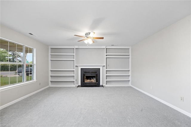 unfurnished living room with a ceiling fan, baseboards, carpet floors, and a fireplace with raised hearth