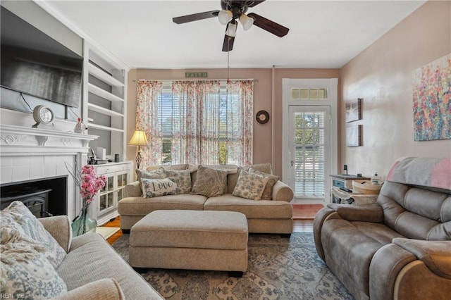 living room featuring ceiling fan, wood finished floors, and a tile fireplace