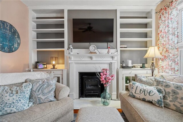 living area with a ceiling fan, a fireplace, and built in features