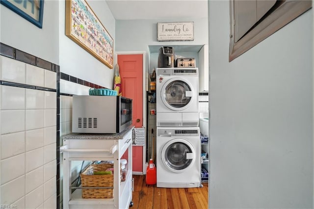 washroom featuring stacked washer / dryer, tile walls, and wood finished floors