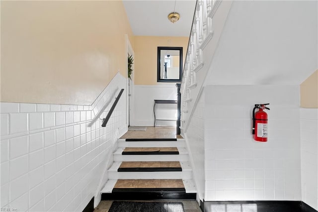 stairway with a wainscoted wall