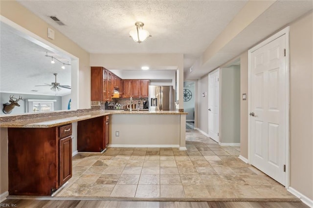kitchen with stainless steel fridge with ice dispenser, a peninsula, a textured ceiling, decorative backsplash, and a ceiling fan