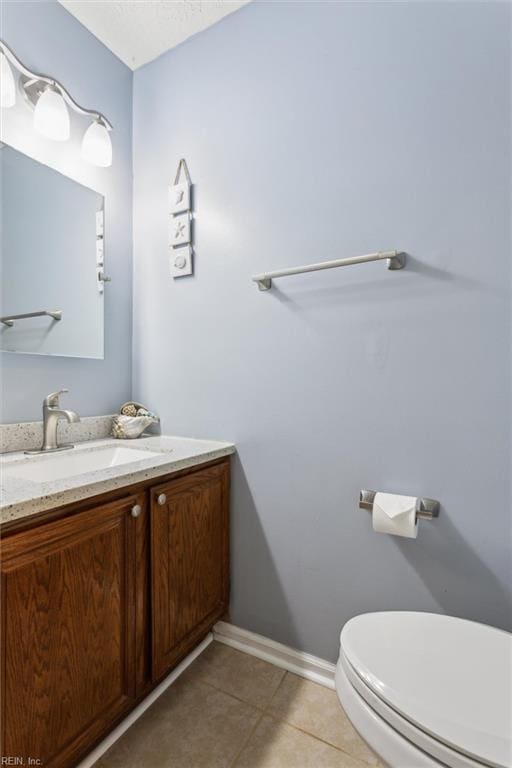 half bathroom featuring tile patterned floors, toilet, vanity, and baseboards