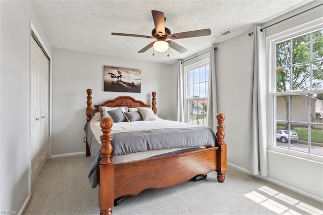 bedroom with carpet floors, baseboards, a textured ceiling, ceiling fan, and a closet