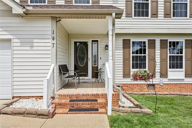 doorway to property with covered porch and a shingled roof