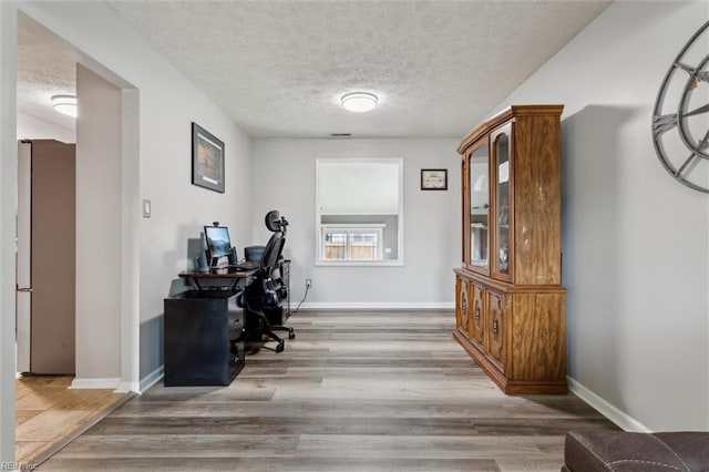 office featuring wood finished floors, a textured ceiling, and baseboards