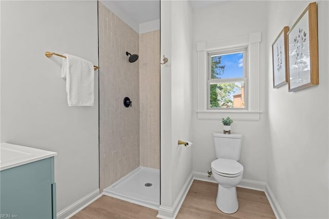 full bath with wood finished floors, tiled shower, toilet, and baseboards