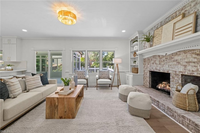living room with recessed lighting, a fireplace, light wood finished floors, crown molding, and built in shelves