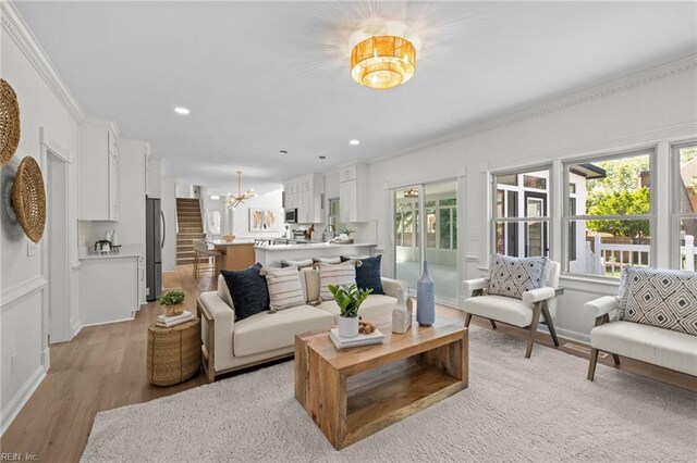 living room with a chandelier, light wood-style flooring, crown molding, recessed lighting, and baseboards