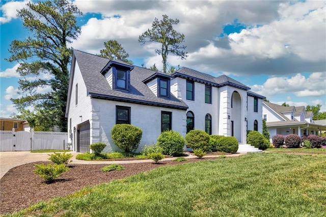 view of front facade featuring a gate, an attached garage, concrete driveway, brick siding, and roof with shingles