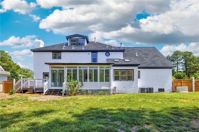 rear view of house featuring a sunroom, a shingled roof, a chimney, a deck, and central AC