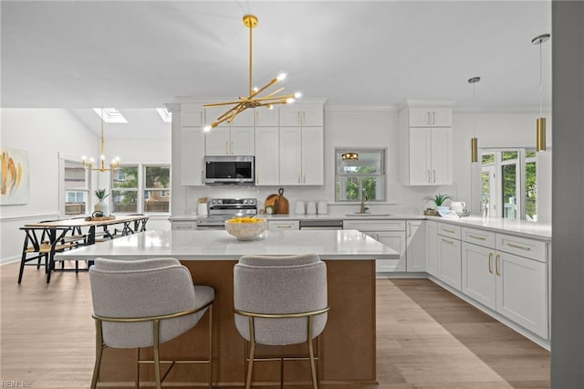 kitchen with appliances with stainless steel finishes, a chandelier, light countertops, and plenty of natural light