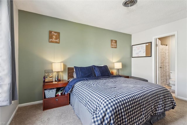 bedroom featuring carpet flooring, baseboards, a textured ceiling, and ensuite bath