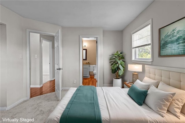 carpeted bedroom featuring baseboards and connected bathroom