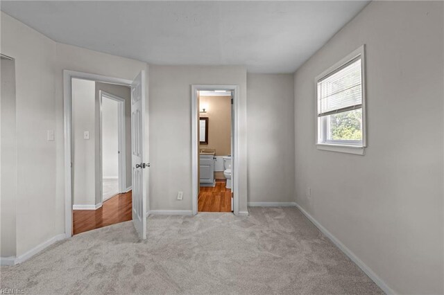 unfurnished bedroom featuring carpet, baseboards, and connected bathroom