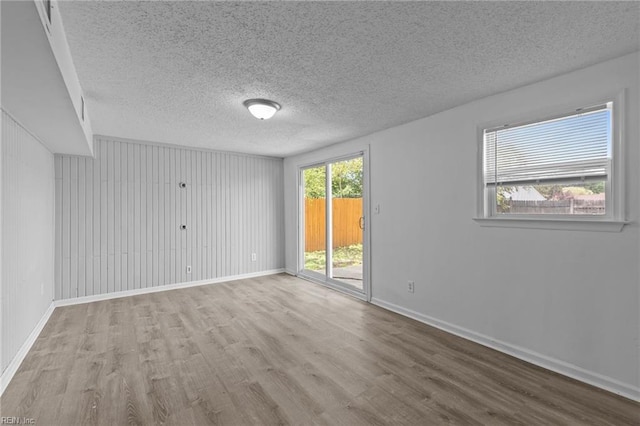 empty room featuring wood finished floors, a textured ceiling, and baseboards