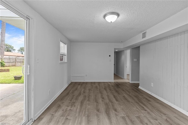 spare room featuring a textured ceiling, wood finished floors, and baseboards