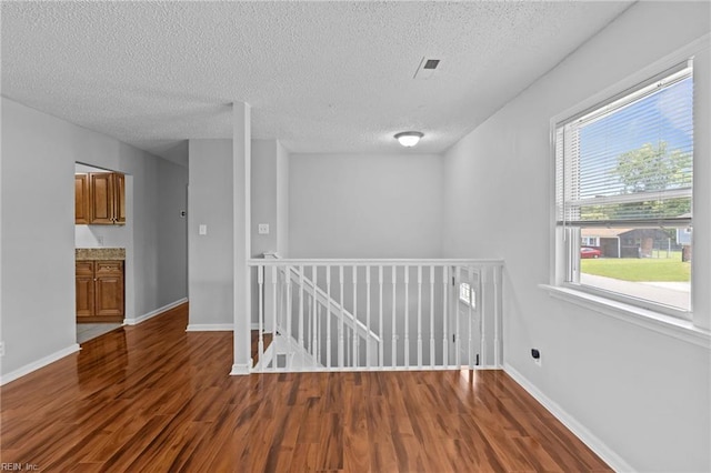 unfurnished room with wood finished floors, a textured ceiling, and baseboards