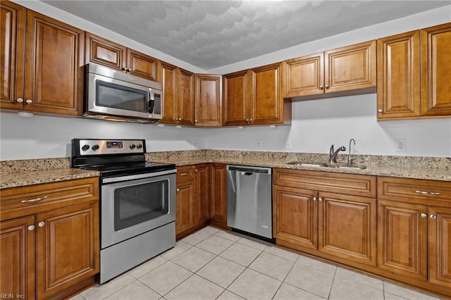 kitchen with stainless steel appliances, a sink, and brown cabinetry