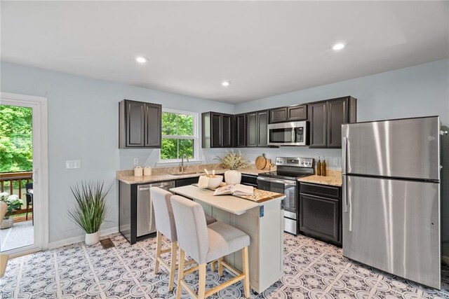 703 Lakeview Cv, Smithfield, VA 23430 - kitchen with stainless steel appliances, light countertops, a kitchen island, a sink, and a breakfast bar area