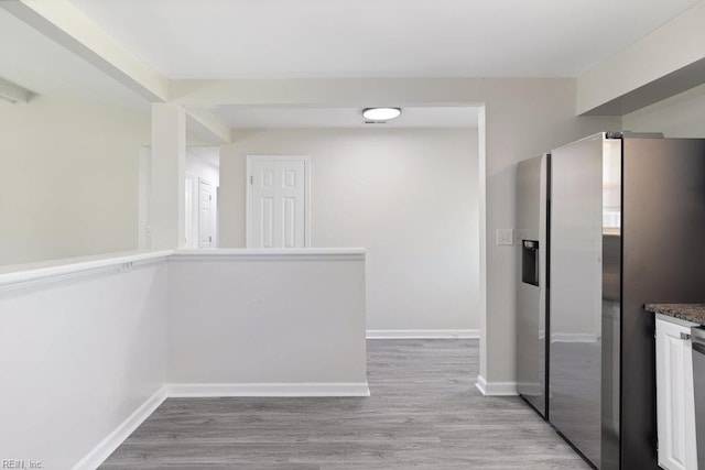 kitchen with stainless steel fridge with ice dispenser, light wood-style floors, baseboards, and dark countertops