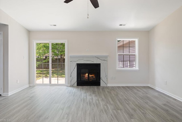 unfurnished living room with wood finished floors, a ceiling fan, baseboards, and a premium fireplace