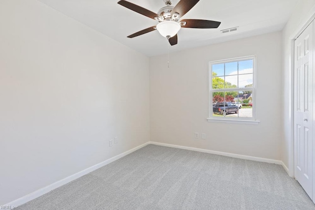 carpeted spare room featuring ceiling fan and baseboards