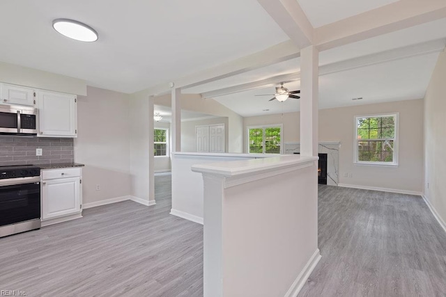 kitchen with stainless steel microwave, range with electric stovetop, light wood finished floors, and healthy amount of natural light
