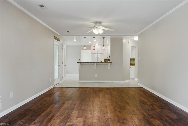unfurnished living room featuring a ceiling fan, ornamental molding, hardwood / wood-style floors, and baseboards