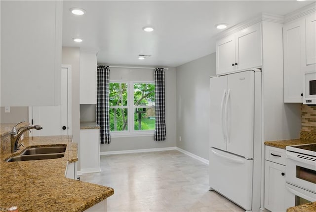 kitchen featuring white appliances, a sink, white cabinetry, baseboards, and light stone counters